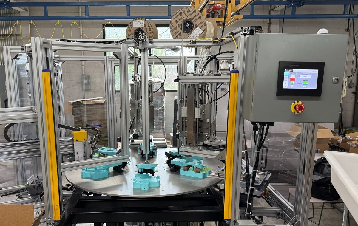 A rotary indexing assembly cell built by TMD, with an aluminum extrusion frame, light-curtain guarding and an operator HMI.