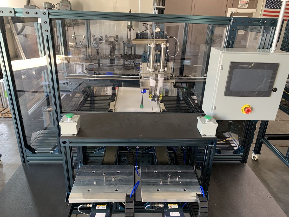 The 6-axis elastic stapling machine built by TMD on the shop floor — extruded aluminum frame, gantry-mounted stapler head, fixture plates at the infeed and an operator HMI.