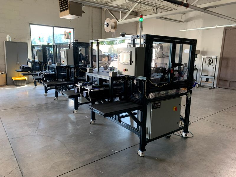 A custom automation machine built by TMD standing on the shop floor, with conveyor and guarded frame.